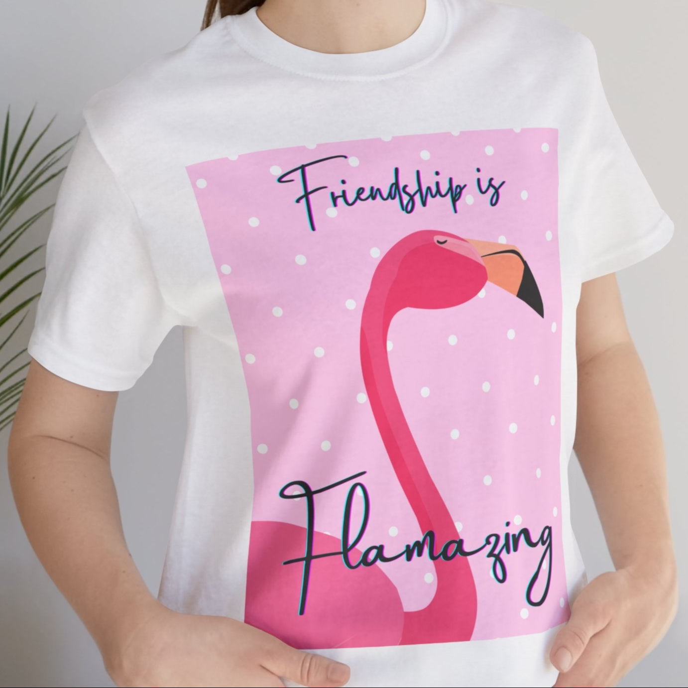 Person wearing a white t-shirt with a flamingo graphic and text, standing indoors.